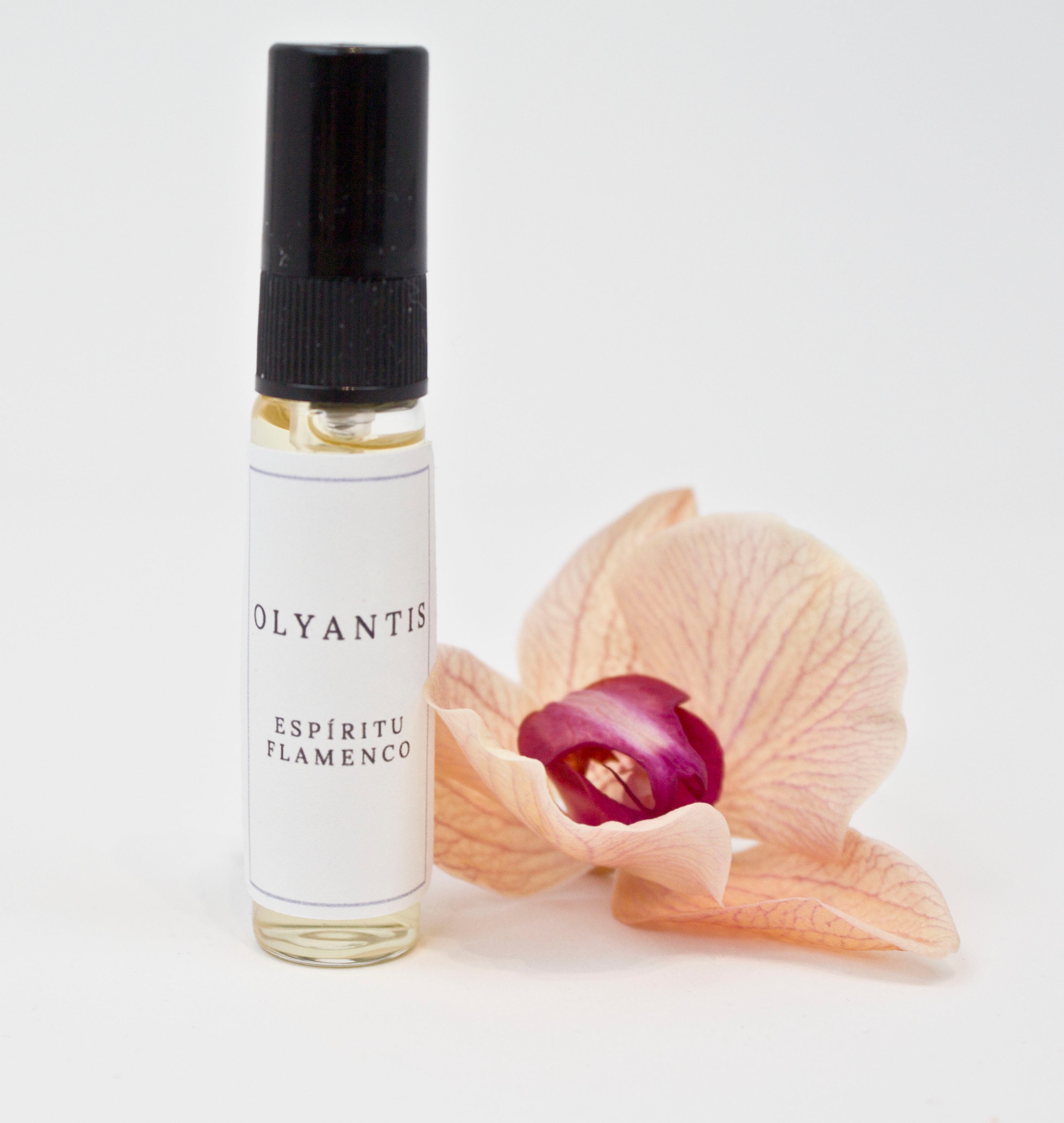 Olyantis's Espíritu Flamenco 5 ml perfume glass bottle beside a golden-burgundy flower.