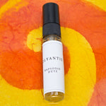 Olyantis's  Rapsodie D'Été 5 ml perfume glass bottle on an orange, colorful background.