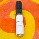 Olyantis's  Rapsodie D'Été 5 ml perfume glass bottle on an orange, colorful background.