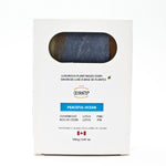 A white rectangular box of Olyantis's Peaceful Ocean plant-based soap, featuring a circular cutout window showing the dark blue soap bar inside. The packaging includes text detailing the scent and ingredients. Made in Canada